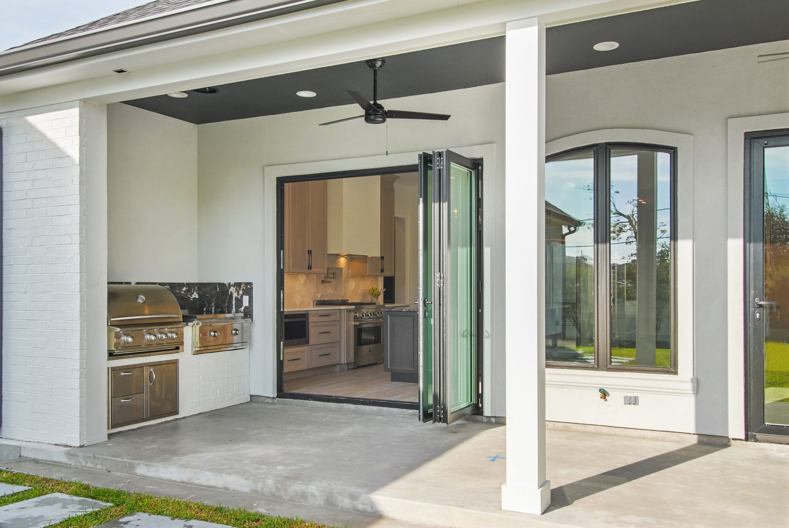 Indoor-outdoor living kitchen to back patio grill area folding doors of Dogwood House new construction luxury home designed and built by DMG
