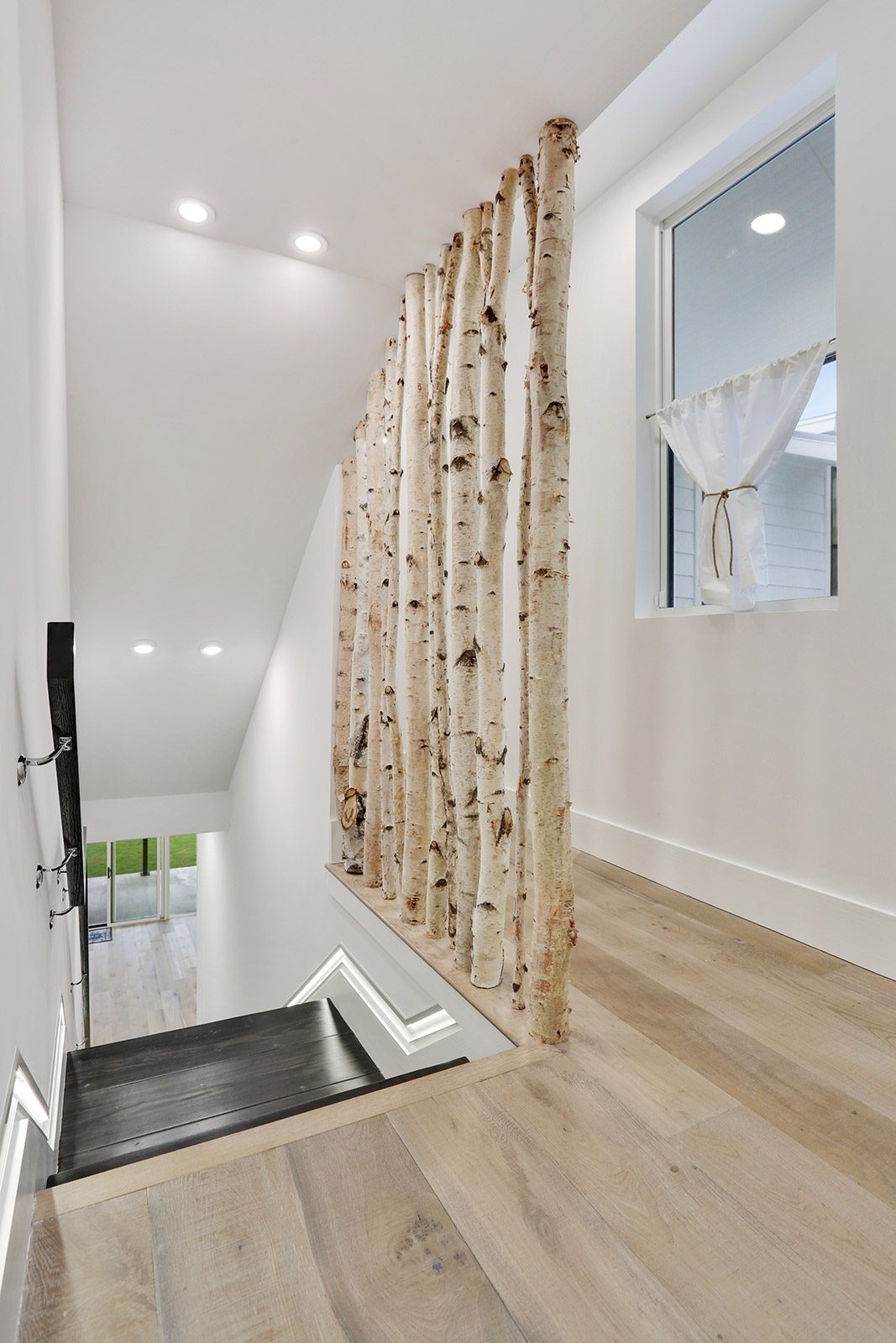 Stairway with custom birch tree railing in Elmeer House luxury new construction home designed and built by DMG Design+Build