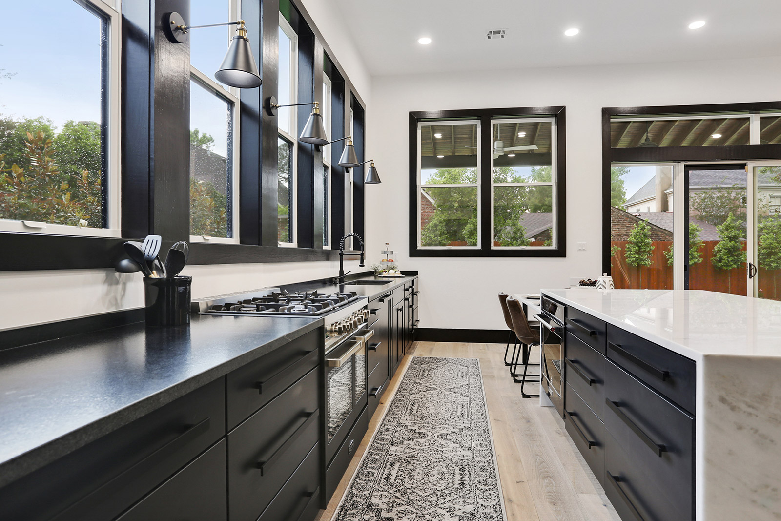 Luxury Modern Custom Kitchen with Black cabinets and waterfall island in Elmeer House new construction home designed and built by DMG